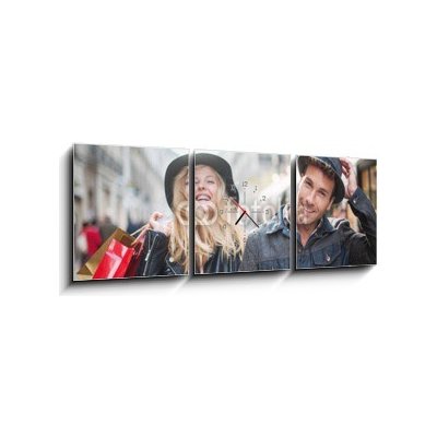 Obraz s hodinami 3D třídílný - 150 x 50 cm - a trendy young couple wearing hats walking in the city in autum módní mladý pár nosí klobouky chůzi ve městě v podzimní
