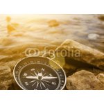 Weblux 60262537 Samolepka fólie compass on the shore at sunrise kompas na pobřeží při východu slunce rozměry 100 x 73 cm