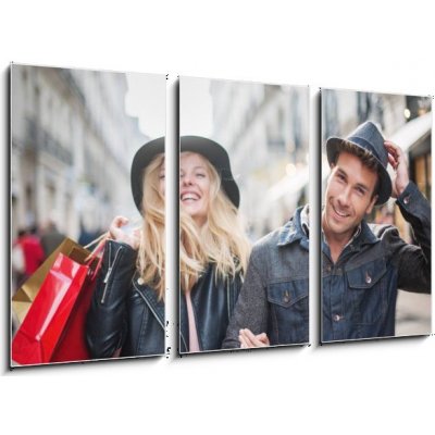 Obraz 3D třídílný - 90 x 50 cm - a trendy young couple wearing hats walking in the city in autum módní mladý pár nosí klobouky chůzi ve městě v podzimní – Hledejceny.cz