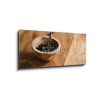 Obraz 1D panorama - 120 x 50 cm - black dry pepper fall into wooden bowl on table Černý suchý pepř spadl do dřevěné misky na stole