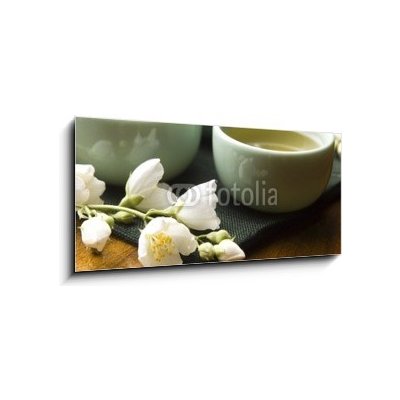 Skleněný obraz 1D panorama - 120 x 50 cm - Green tea with jasmine in cup and teapot on wooden table Zelený čaj s jasmínem v šálku a konvici na dřevěném stole – Zbozi.Blesk.cz